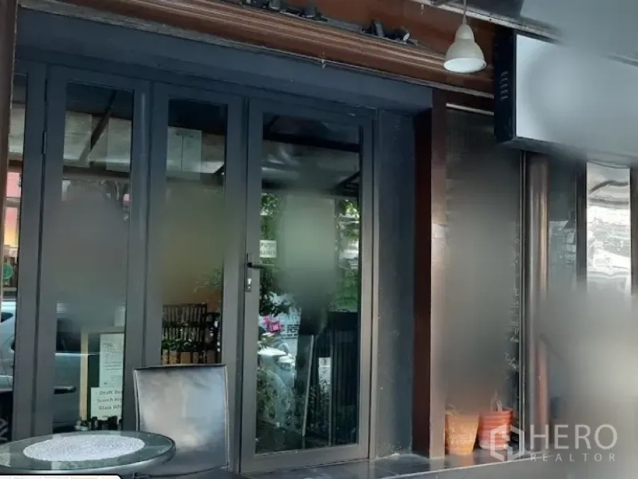 Shophouse for rent in Watthana, Bangkok - Street-level shophouse frontage with wide glass doors and a small patio seating area in Thonglor.