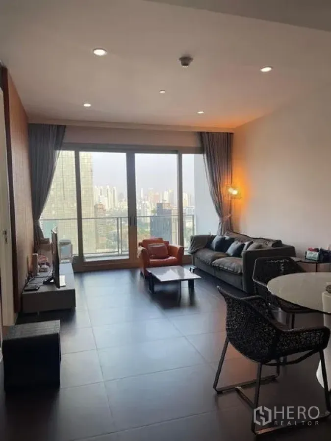 Condominium for rent in Pathum Wan, Bangkok - Bright living room with floor-to-ceiling windows, sofa and Bangkok skyline view