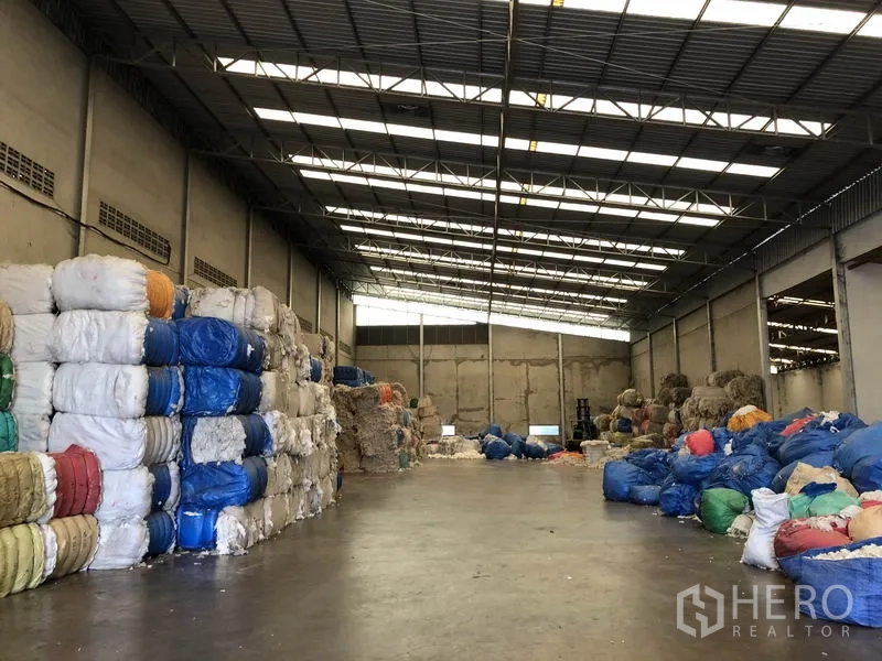 Factory for rent in Bang Bua Thong, Nonthaburi - Wide warehouse bay showing clear-span steel roof and bundled goods on pallets.