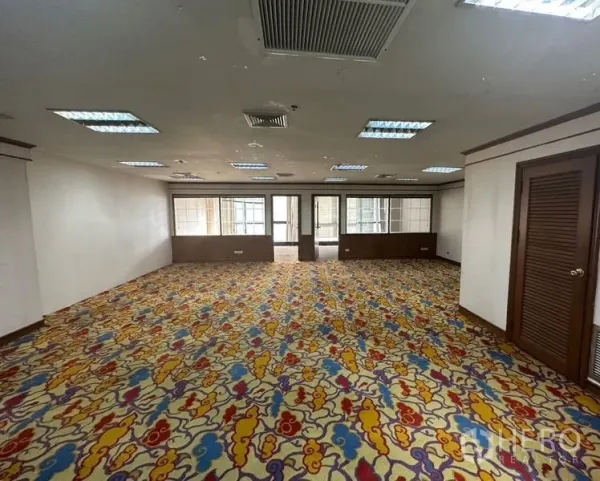 Office Space for rent - Large open-plan office with colorful carpet, grid ceiling lights and central air-conditioning leading to partitioned rooms.