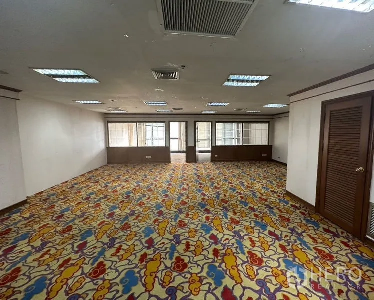 Office Space for rent - Large open-plan office with colorful carpet, grid ceiling lights and central air-conditioning leading to partitioned rooms.