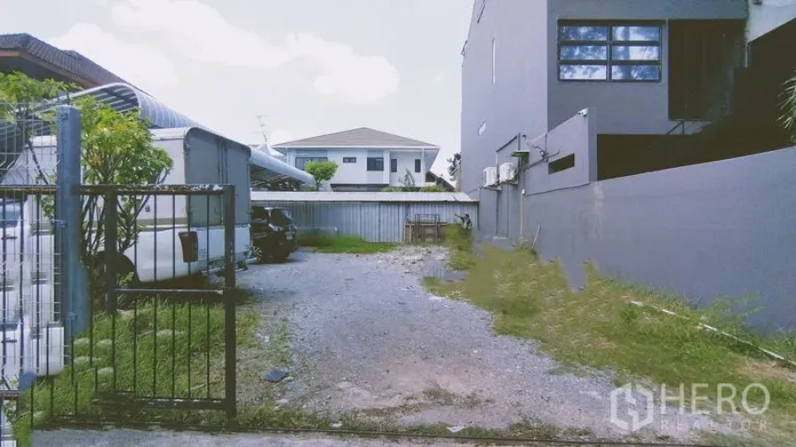 Home Office for rent in Chatuchak, Bangkok - Gated gravel parking area beside the building.
