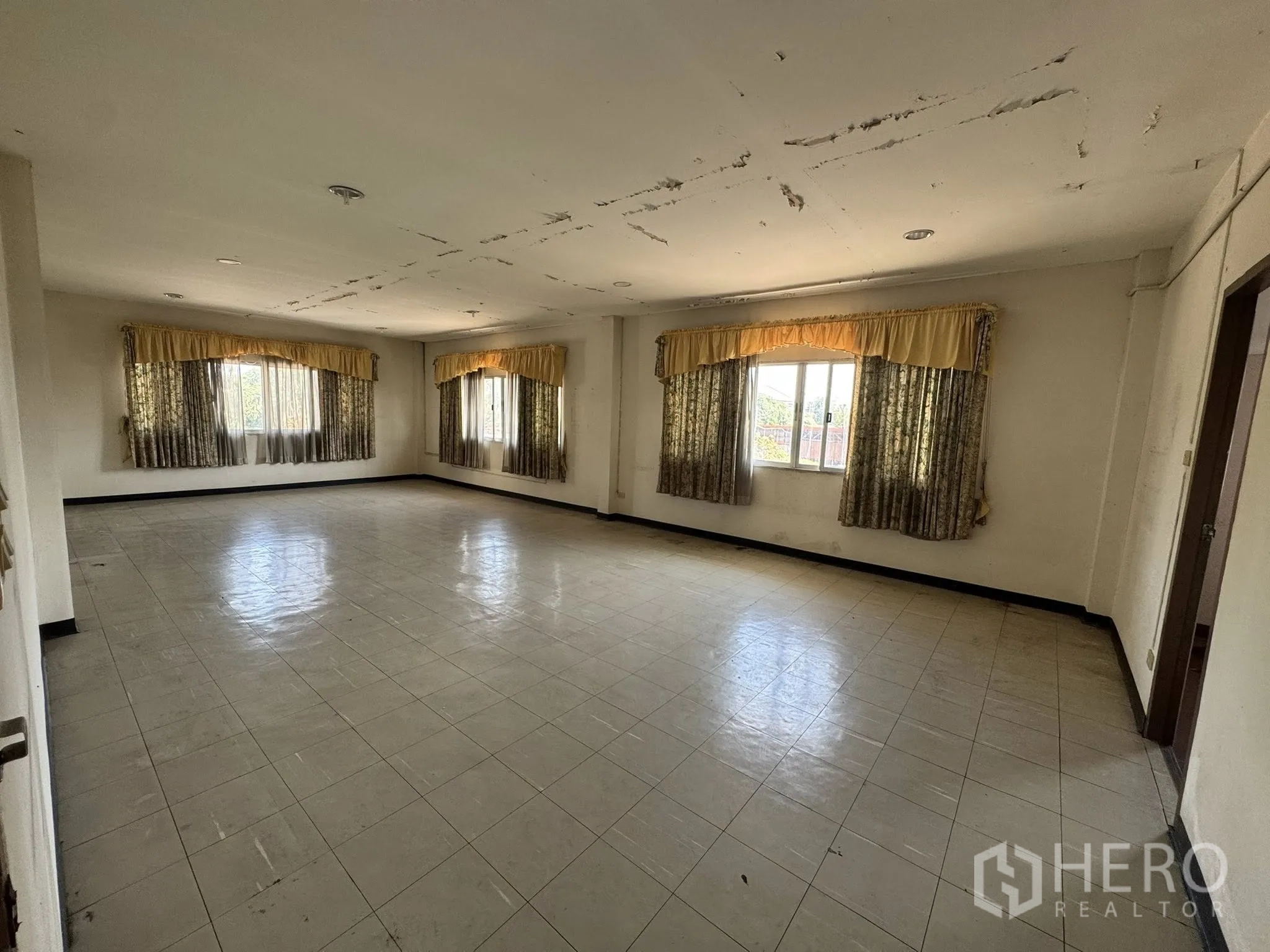 Warehouse for rent in Mueang Samut Sakhon, Samut Sakhon - Large open room with multiple windows, yellow curtains and tiled flooring.