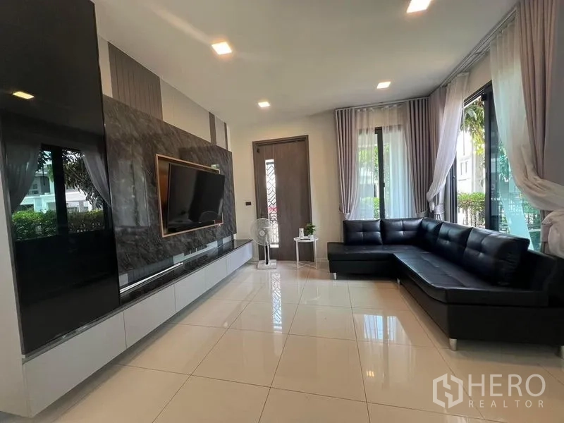 Detached House for rent or sale - Living room with black L-shaped sofa facing the TV wall.