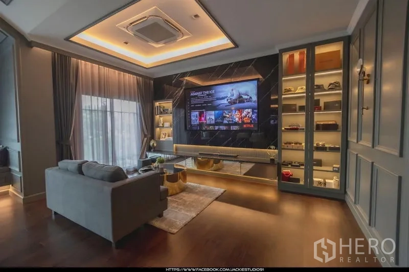 บ้าน ขายในPak Kret, Nonthaburi - ห้องนั่งเล่นครอบครัว ผนังทีวีขนาดใหญ่ ไฟซ่อน และชั้นโชว์กระจก