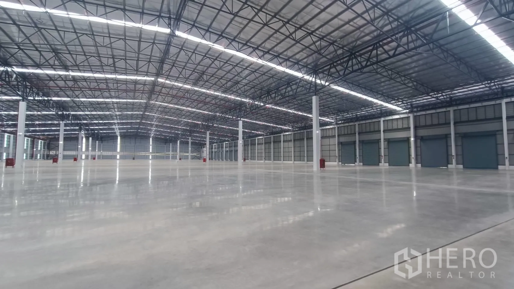 工厂 for rent in Bang Sao Thong, Samut Prakan - 高挑仓库内部，混凝土地面与钢结构屋架，多个卷闸门。