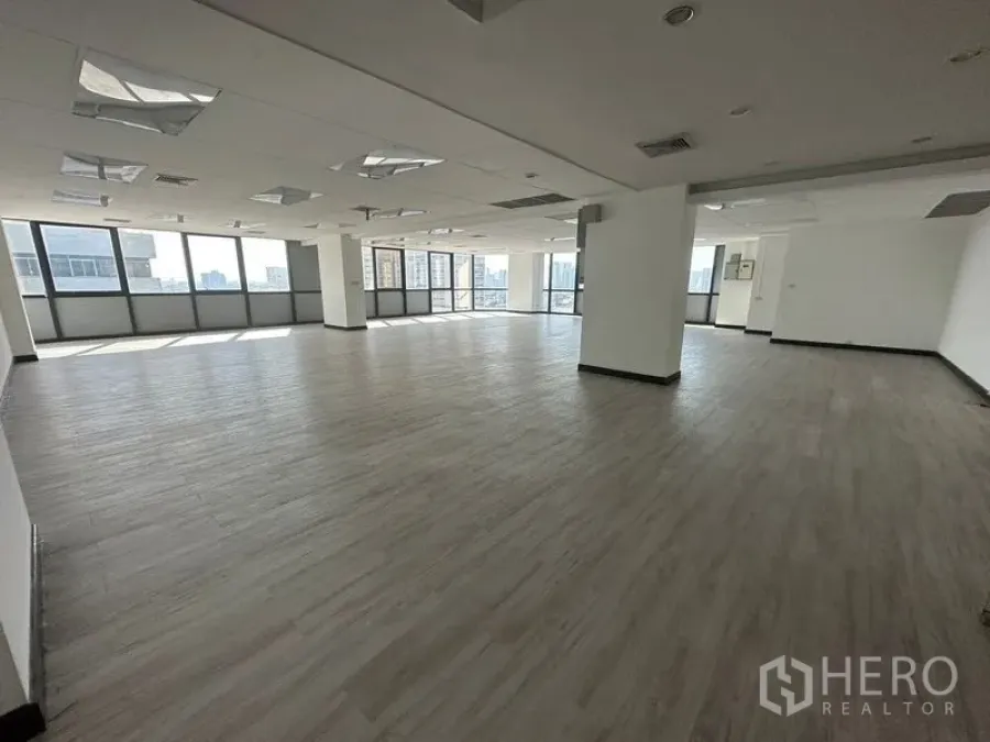 Office Space for rent or sale - Open office with columns, vinyl flooring, and panoramic windows facing Ekkamai.