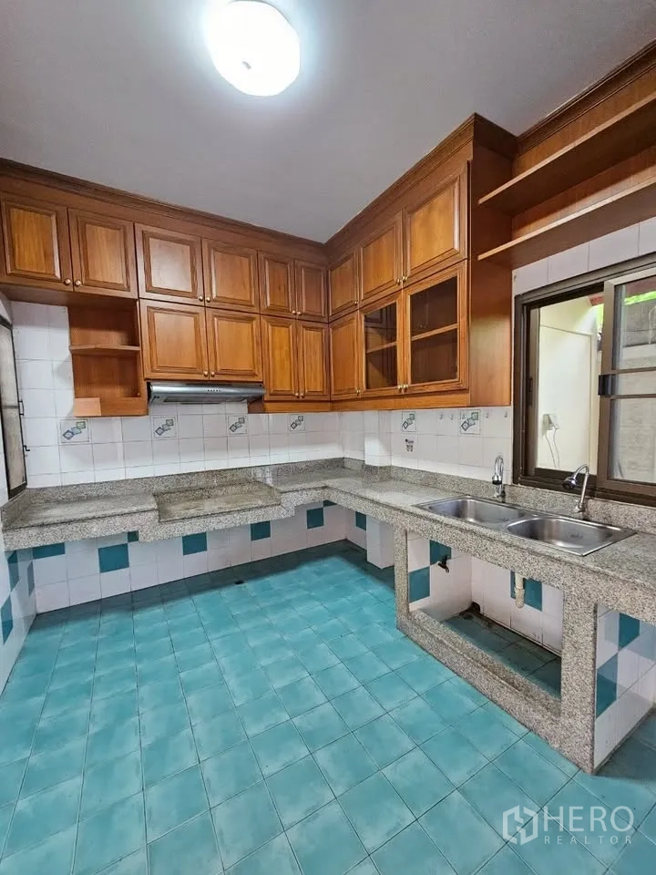 Home Office for rent in Wang Thonglang, Bangkok - U‑shaped kitchen with granite counters, wooden cabinets, tiled walls and double sink.