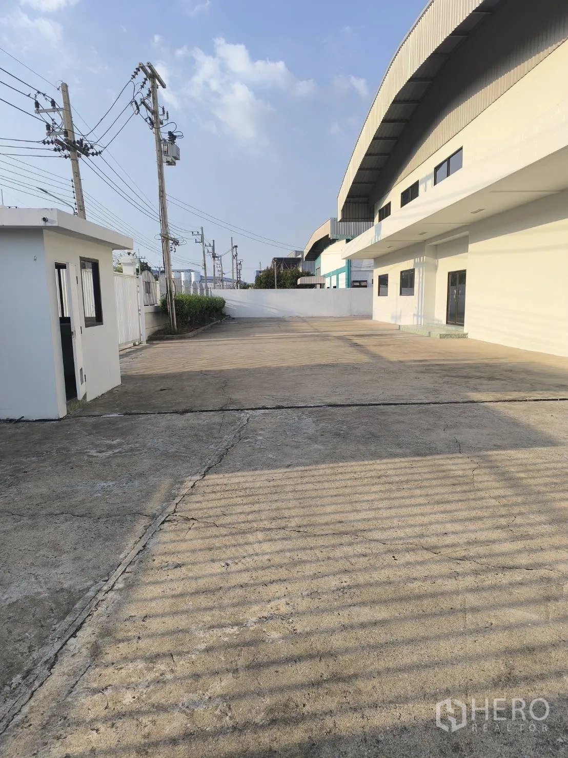 工厂 for sale in Khlong Luang, Pathum Thani - 建筑旁宽阔的混凝土车道与保安岗亭。