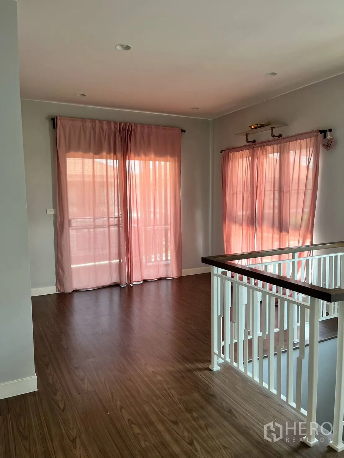 Detached House for rent or sale in Lam Luk Ka, Pathum Thani - Second view of upstairs landing with white balustrade and wood floors.