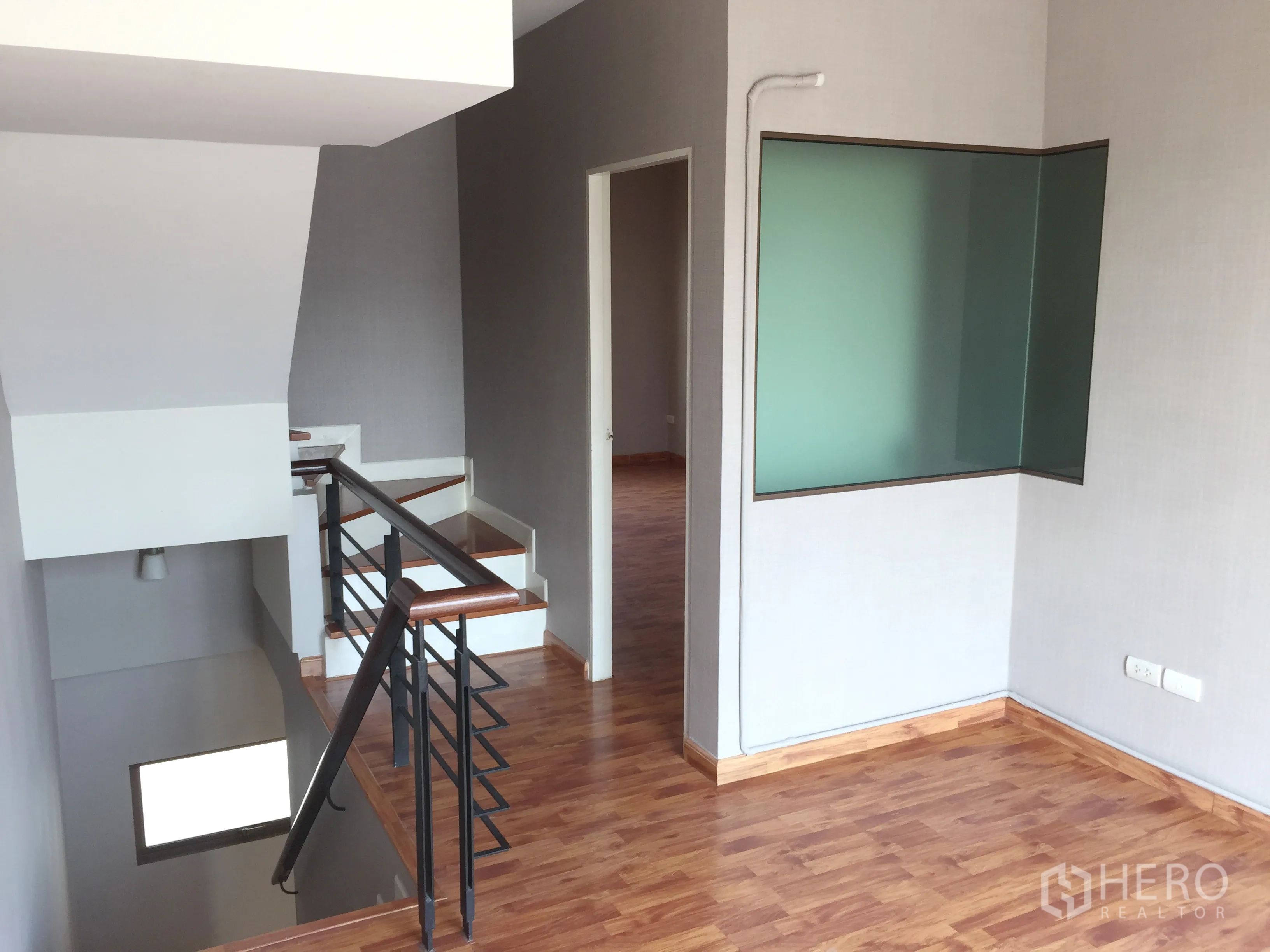 Townhouse for rent or sale in Phra Khanong, Bangkok - Stair landing with wood floors, metal railing, and a corner glass partition.