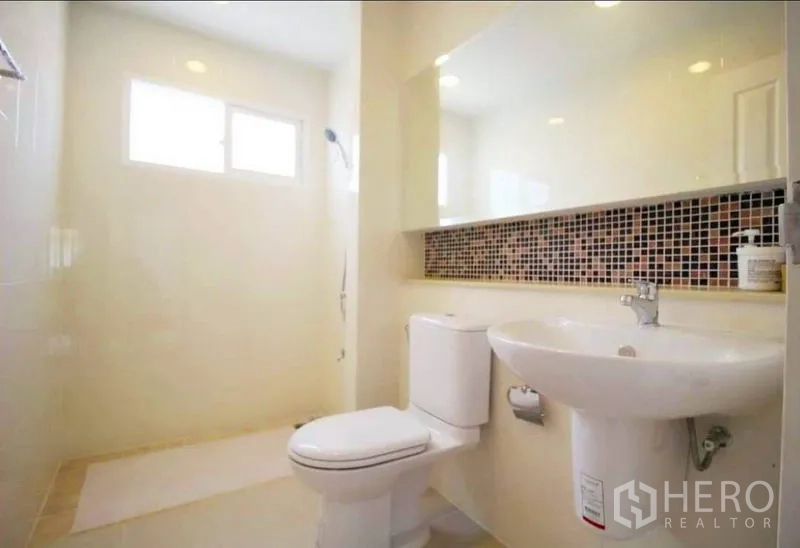 Detached House for rent or sale in Bang Yai, Nonthaburi - Bright bathroom with pedestal sink, toilet and walk-in shower under a window.