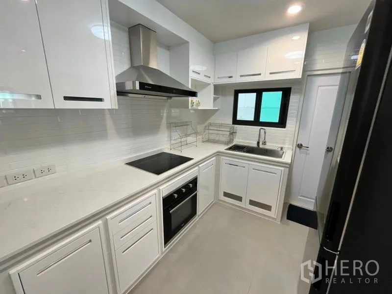 Detached House for rent in Phaya Thai, Bangkok - Sleek white European kitchen with oven, cooktop and extractor hood.