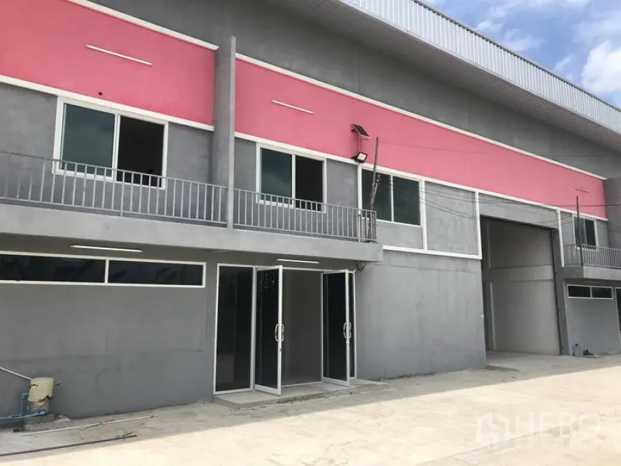 工厂 出租在Sai Noi, Nonthaburi - 现代工厂外立面，粉色装饰带、玻璃入户门与阳台护栏，高位装卸口。