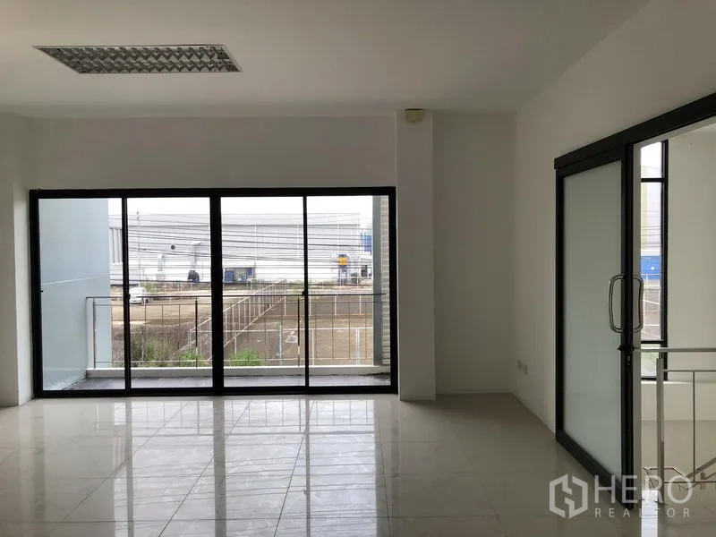 Factory for rent or sale in Bang Phli, Samut Prakan - Office area with large sliding glass doors opening to a balcony and industrial street view.