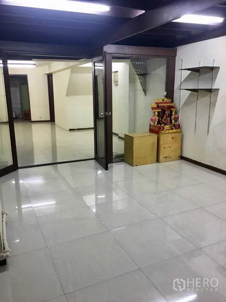 Shophouse for rent in Suan Luang, Bangkok - Bright tiled room with glass partitions, double glass doors and shelving, ideal as office or showroom.