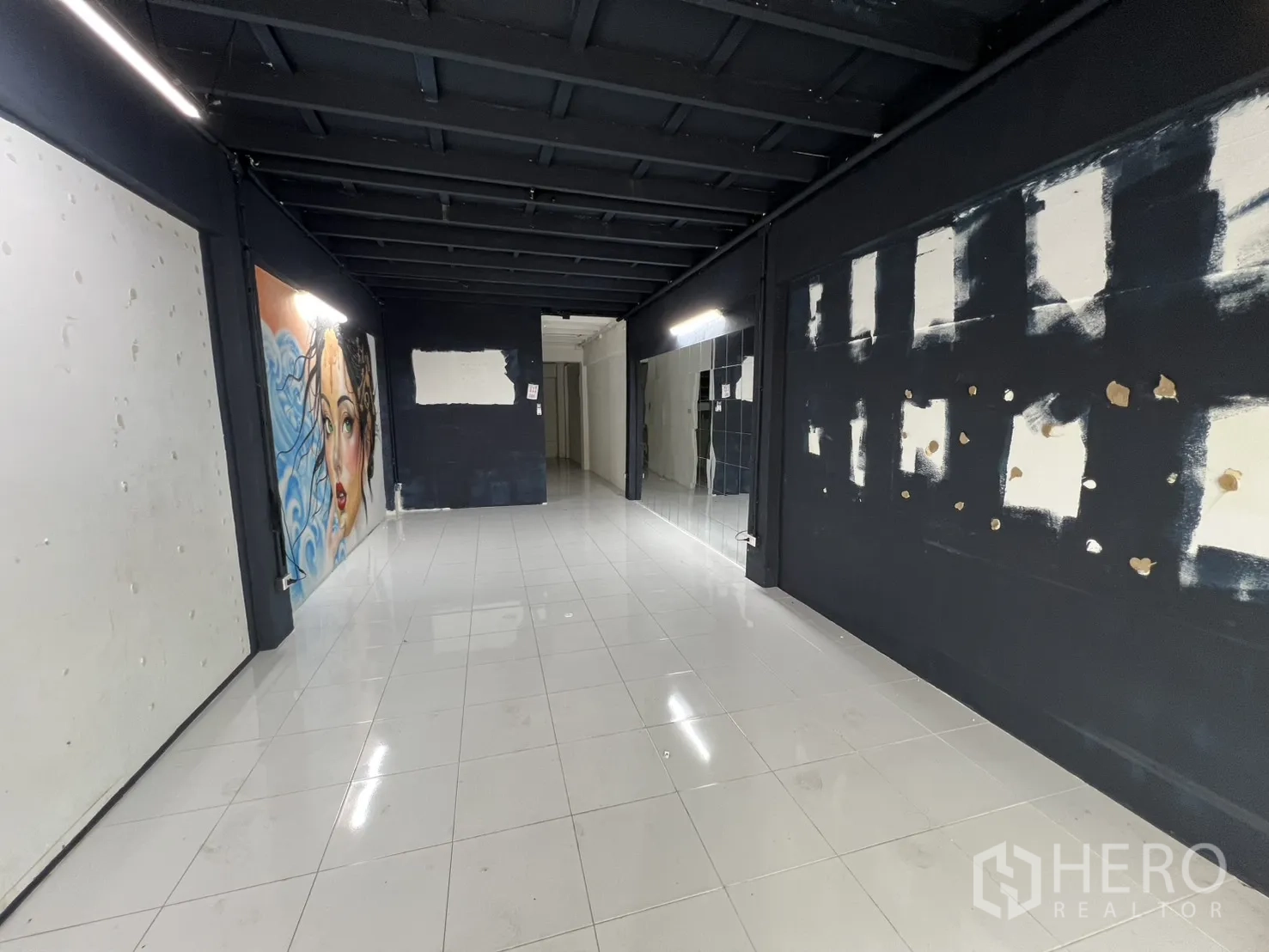 Shophouse for rent or sale in Khlong Toei, Bangkok - Open-plan shop interior with wall mural, mirrors and dark feature walls.