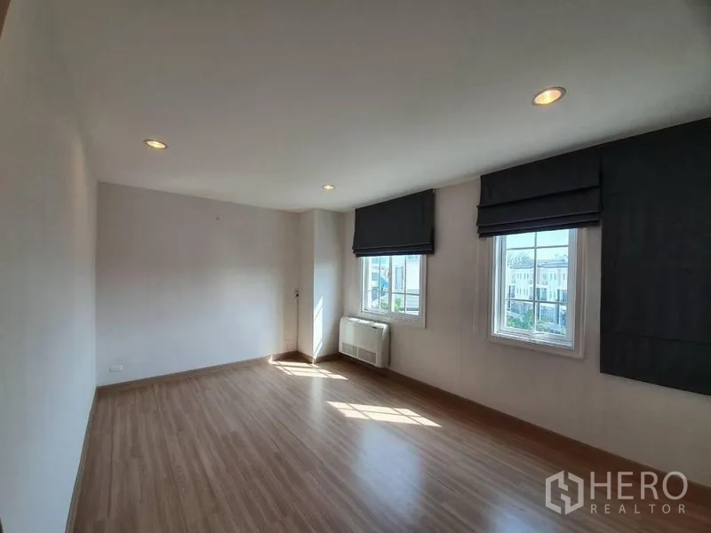 Townhouse for rent in Bang Na, Bangkok - Large corner bedroom with two windows, blackout Roman blinds, recessed lights and wood flooring.
