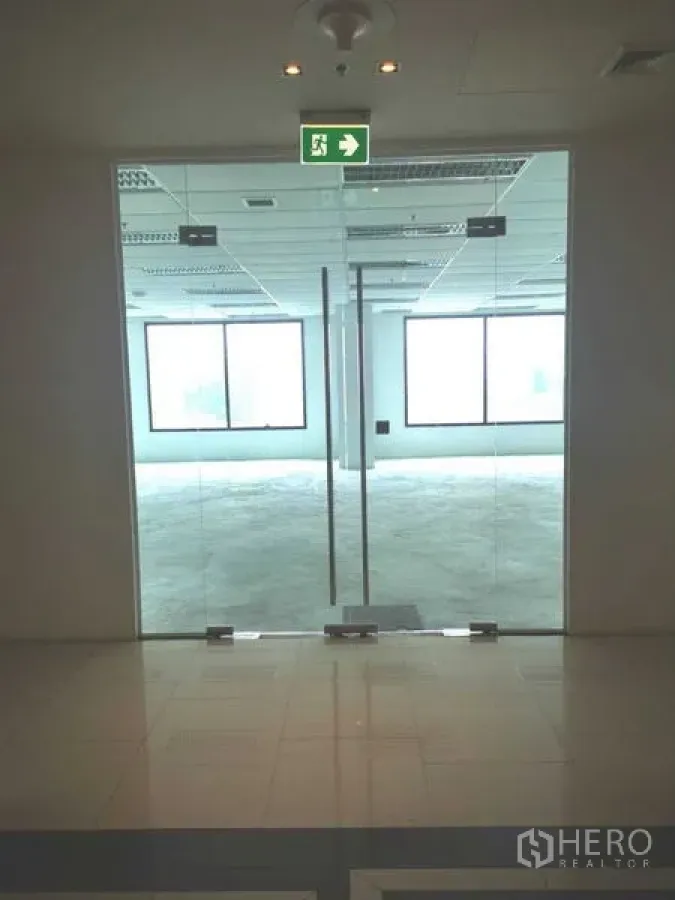 Office Space for rent in Chatuchak, Bangkok - Glass double-door entrance from the lobby into the office unit with exit sign above.