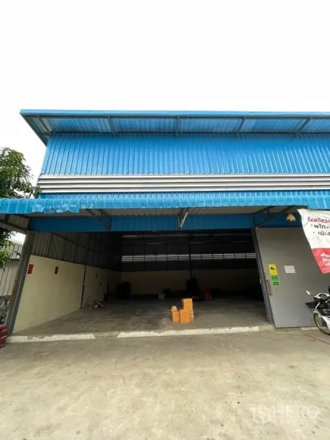 คลังสินค้า ให้เช่าในKhlong Luang, Pathum Thani - ด้านหน้าโกดังผนังเมทัลชีทสีน้ำเงิน มีทางเข้าและลานโหลดของคลุมหลังคา คลองหลวง