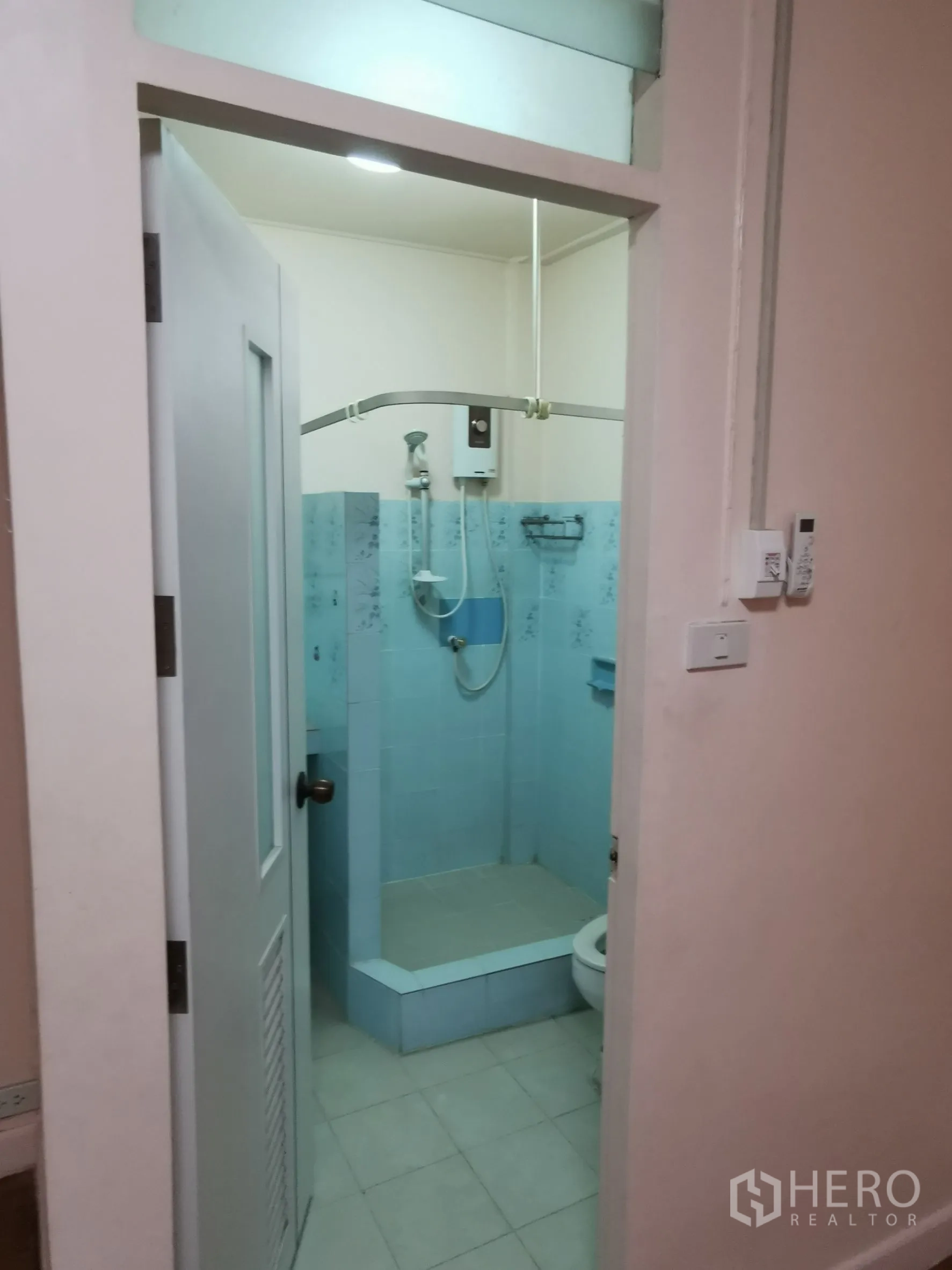 Townhouse for rent in Khlong Toei, Bangkok - Bathroom with blue-tiled shower area, water heater, and toilet.