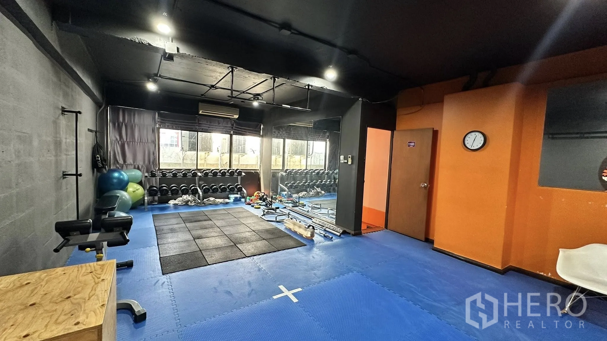 Office Space for rent in Huai Khwang, Bangkok - Workout corner with dumbbell racks by windows, blue mat flooring, and an orange wall.