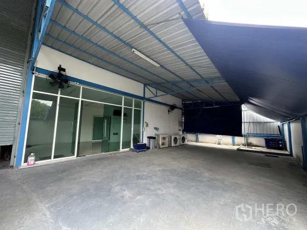 Factory for rent or sale in Bang Yai, Nonthaburi - Covered loading area with glass-front office and outdoor AC condensers.