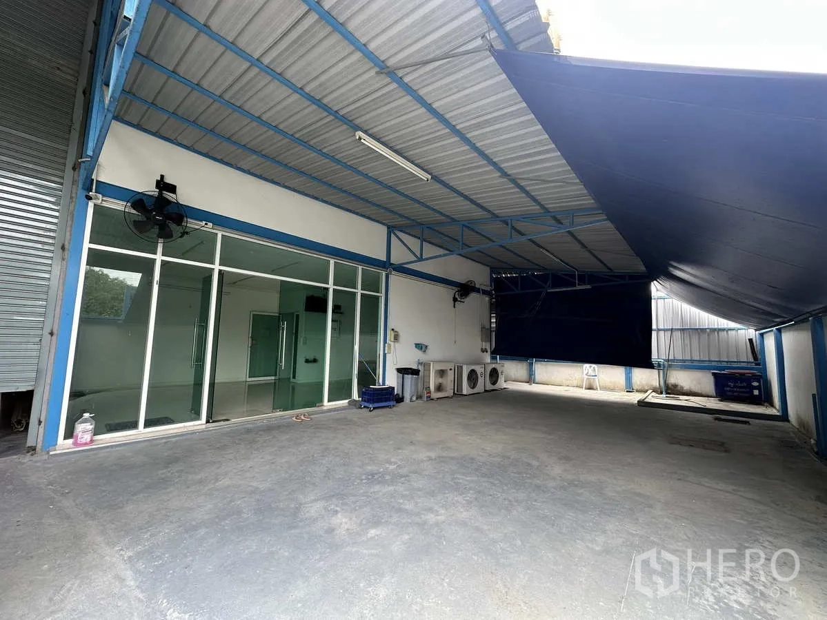 Factory for rent or sale in Bang Yai, Nonthaburi - Covered loading area with glass-front office and outdoor AC condensers.