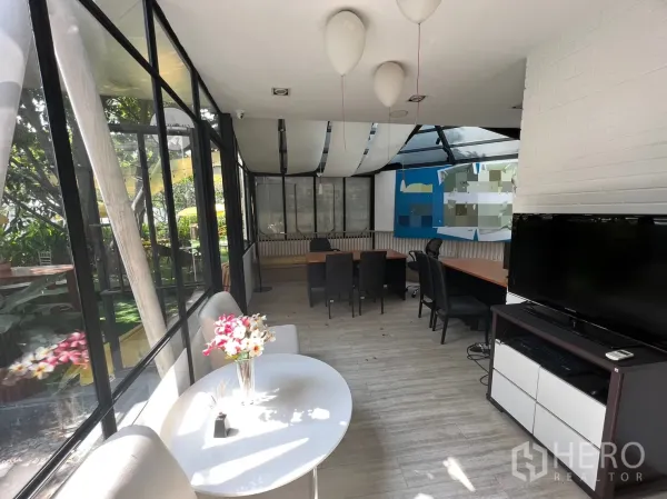 Retail Space for rent in Pathum Wan, Bangkok - Sunlit interior with floor‑to‑ceiling windows, small tables and long workdesk overlooking landscaped greenery.