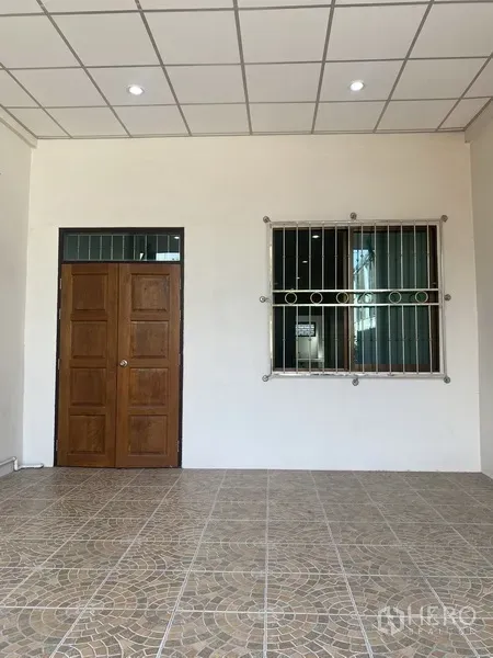 联排别墅 出租在Suan Luang, Bangkok - 带顶前庭，拼花地砖、实木门与带护栏窗户的联排别墅入口。