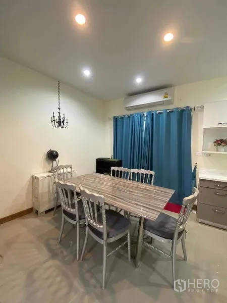 Townhouse for rent in Suan Luang, Bangkok - Dining area with six-seat table under recessed lighting and blue drapes.