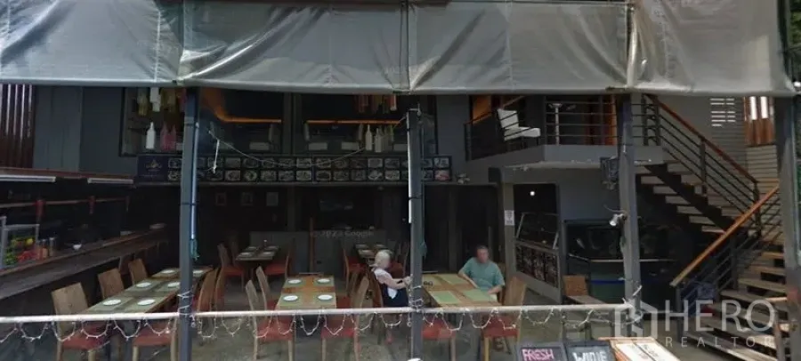 Retail Space for rent in Khlong Toei, Bangkok - Double-height interior featuring dining-style tables, bar counter, and staircase to mezzanine.