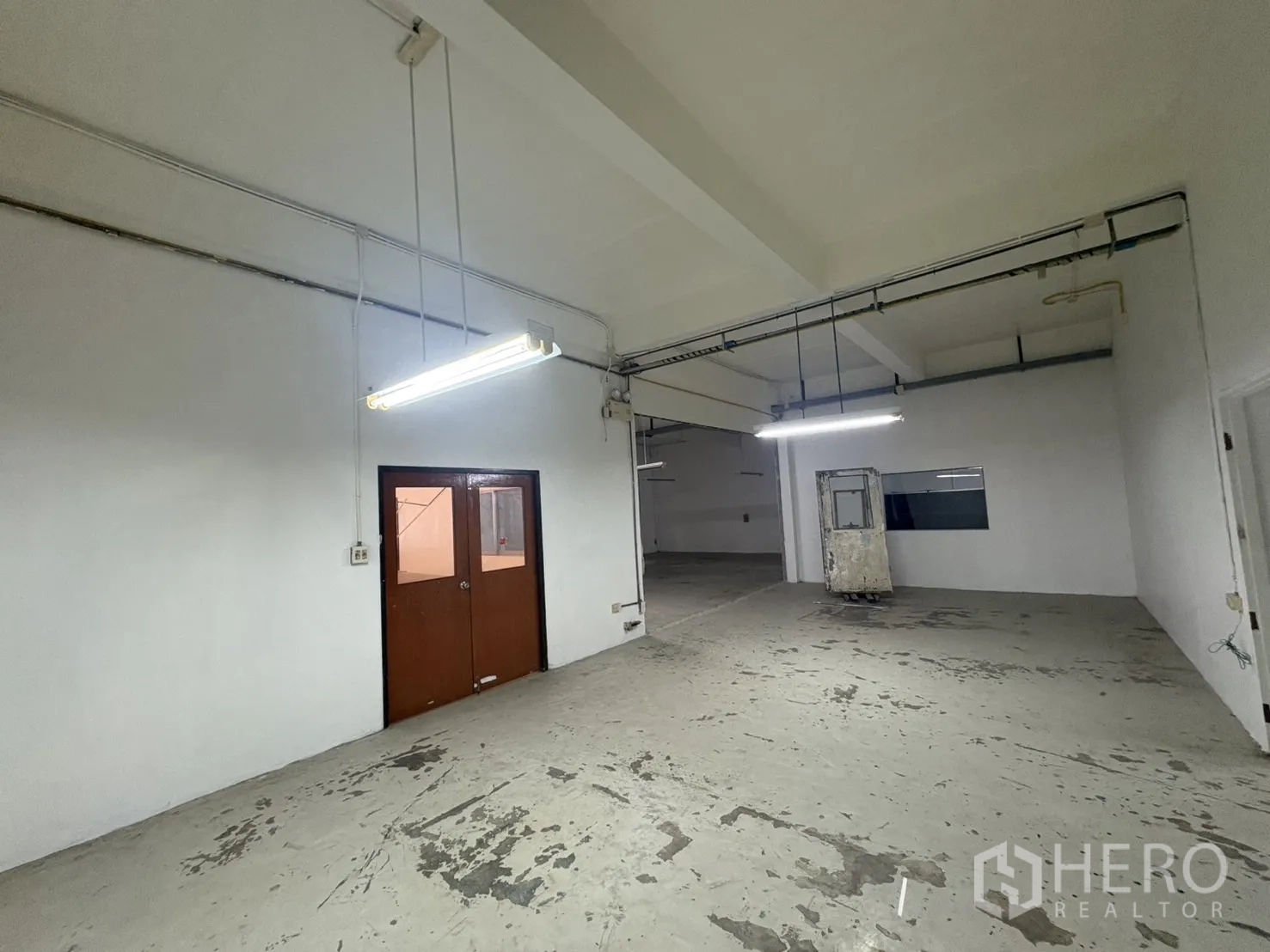 Warehouse for rent in Bang Phli, Samut Prakan - Warehouse zone with double doors and utility lines along walls.