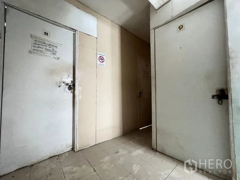 Shophouse for rent in Watthana, Bangkok - Interior corridor with tiled floor and numbered lockable doors, suitable for storage or small rooms.