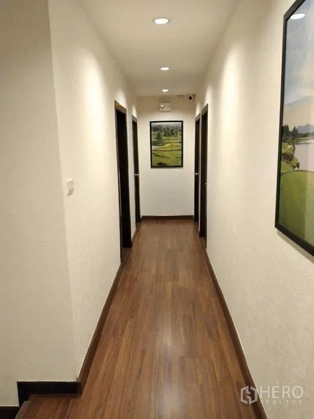 Shophouse for rent in Watthana, Bangkok - Well-lit corridor with wood flooring, multiple room doors, and framed artwork.