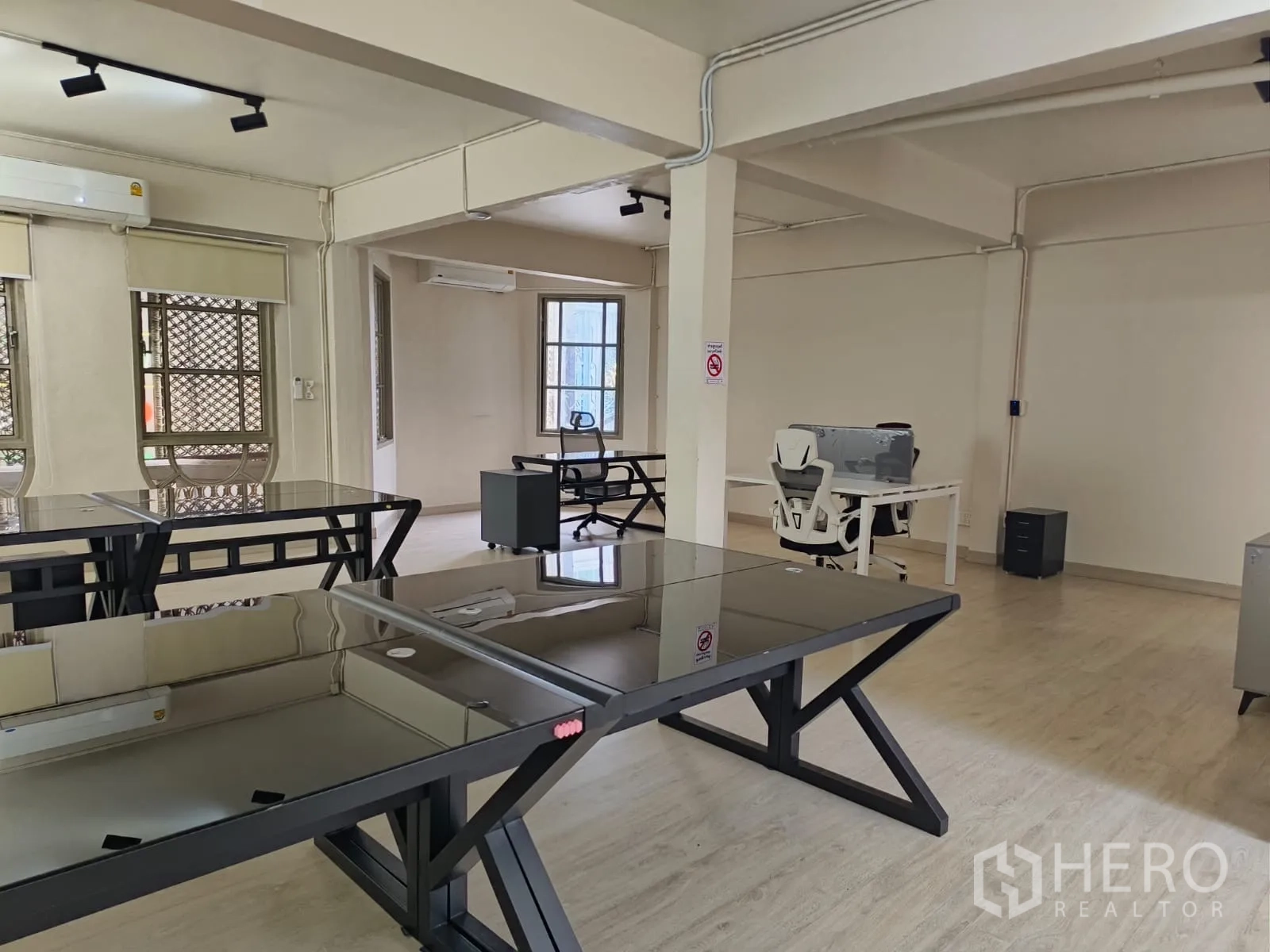 Shophouse for rent in Watthana, Bangkok - Spacious workspace with black glass desks and exposed conduits.