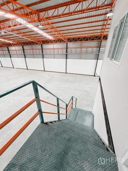 Warehouse for rent or sale in Khlong Luang, Pathum Thani - Metal staircase leading from the warehouse floor up to the mezzanine office window.
