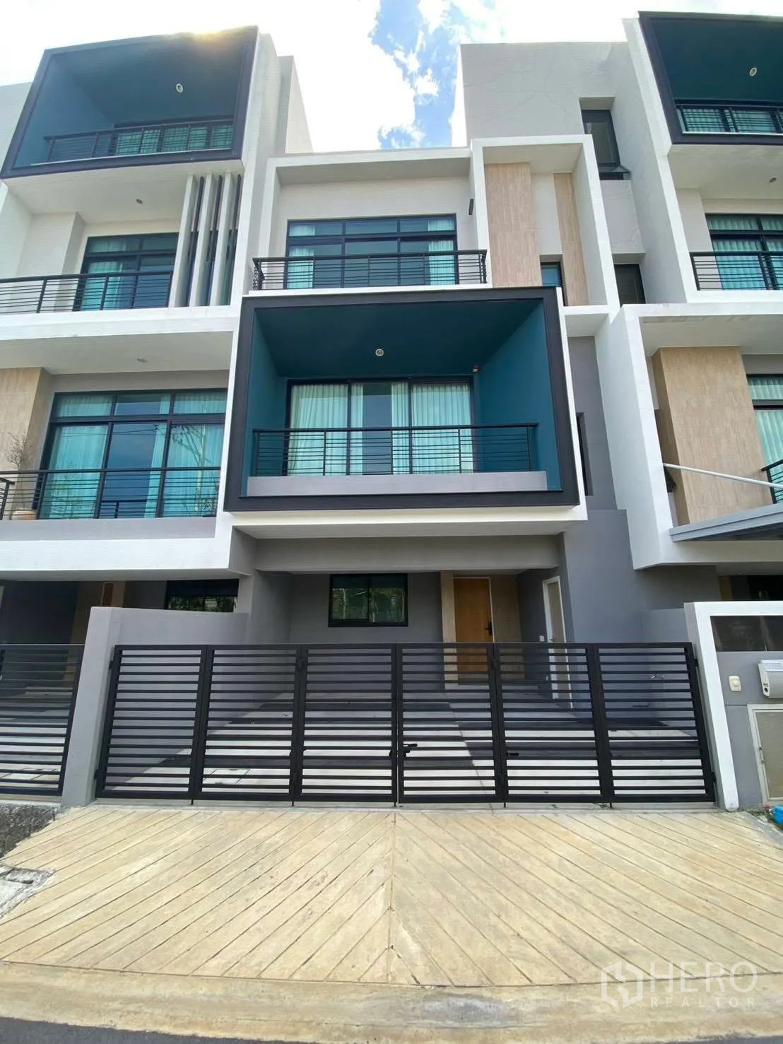 联排别墅 for rent in Bang Kapi, Bangkok - 现代三层联排别墅外观，凹进式阳台与带门庭的停车区。