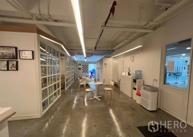Retail Space for rent - Reception and pantry area with small tables, storage cabinets, and linear LED lights.