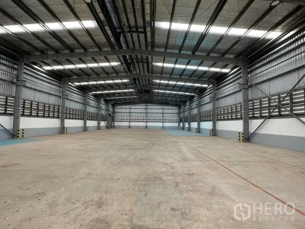 Factory for rent in Mueang Samut Prakan, Samut Prakan - Spacious high-bay warehouse interior with steel beams, skylights and polished concrete floor.