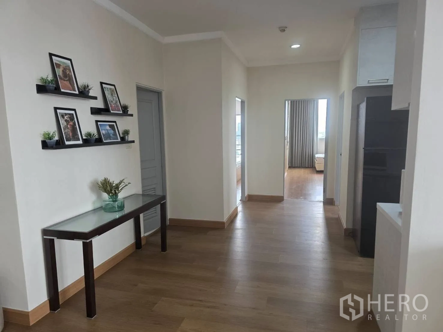 Condominium for rent in Khlong Toei, Bangkok - Hallway with display shelves and console table leading to bedrooms.