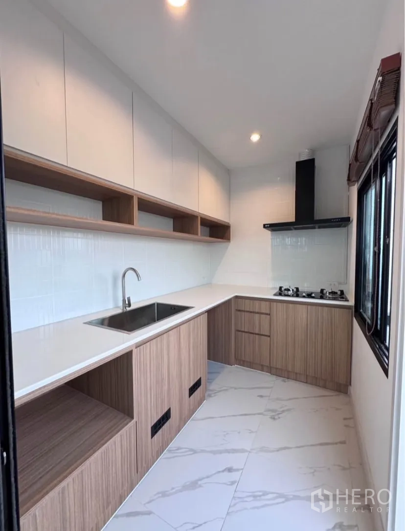 Detached House for rent in Samut Prakan - Fitted L-shaped kitchen with hob, hood and ample storage space.