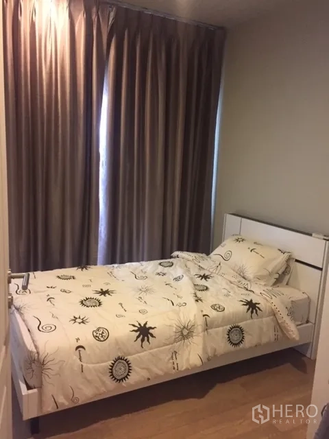 Condominium for rent in Bangkok - Secondary bedroom with single bed, light wood floor and blackout curtains.