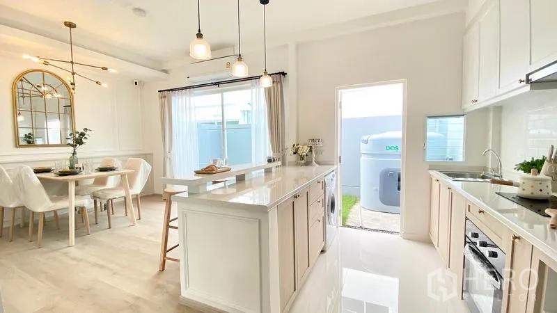 Townhouse for rent in Prawet, Bangkok - Open kitchen with island and dining space facing the backyard, abundant daylight and neutral décor.