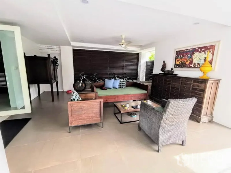 Detached House for rent or sale in Bang Phli, Samut Prakan - Covered terrace lounge with wooden daybed, wicker chair and storage cabinet.