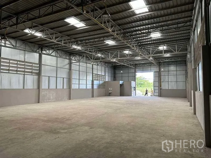 Warehouse for rent in Mueang Pathum Thani, Pathum Thani - Open warehouse hall facing the loading door, side office nook and natural light panels.