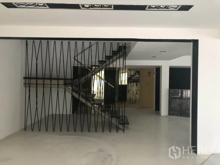 Retail Space for rent in Watthana, Bangkok - Open-plan retail interior with black metal staircase and geometric divider, white walls and polished floors.