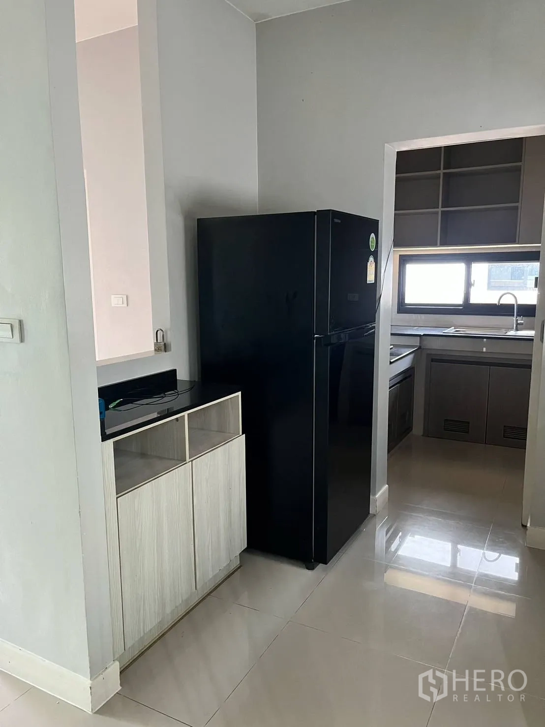 Detached House for rent or sale in Lam Luk Ka, Pathum Thani - View to kitchen area with black refrigerator and glossy tiled floor.