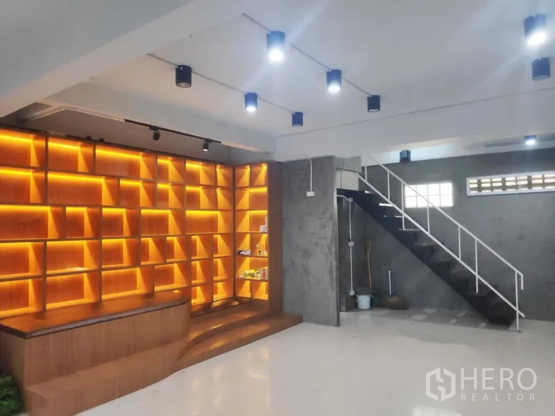带办公室的家 出租在Khlong Toei, Bangkok - 带暖色背光的木质展示架与开放楼梯，适合前台或陈列区。