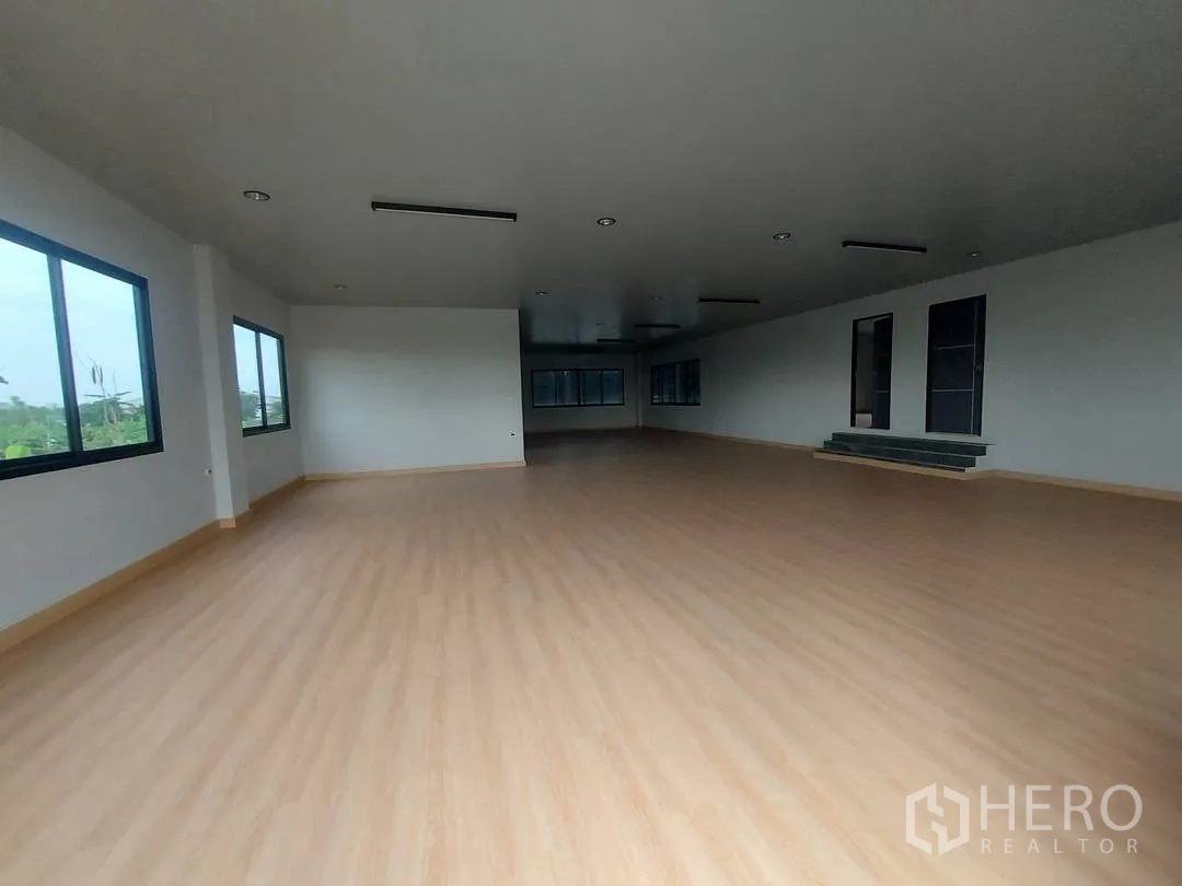Factory for rent in Krathum Baen, Samut Sakhon - Spacious upper-level open office with wood-look flooring, large windows, and recessed lighting.